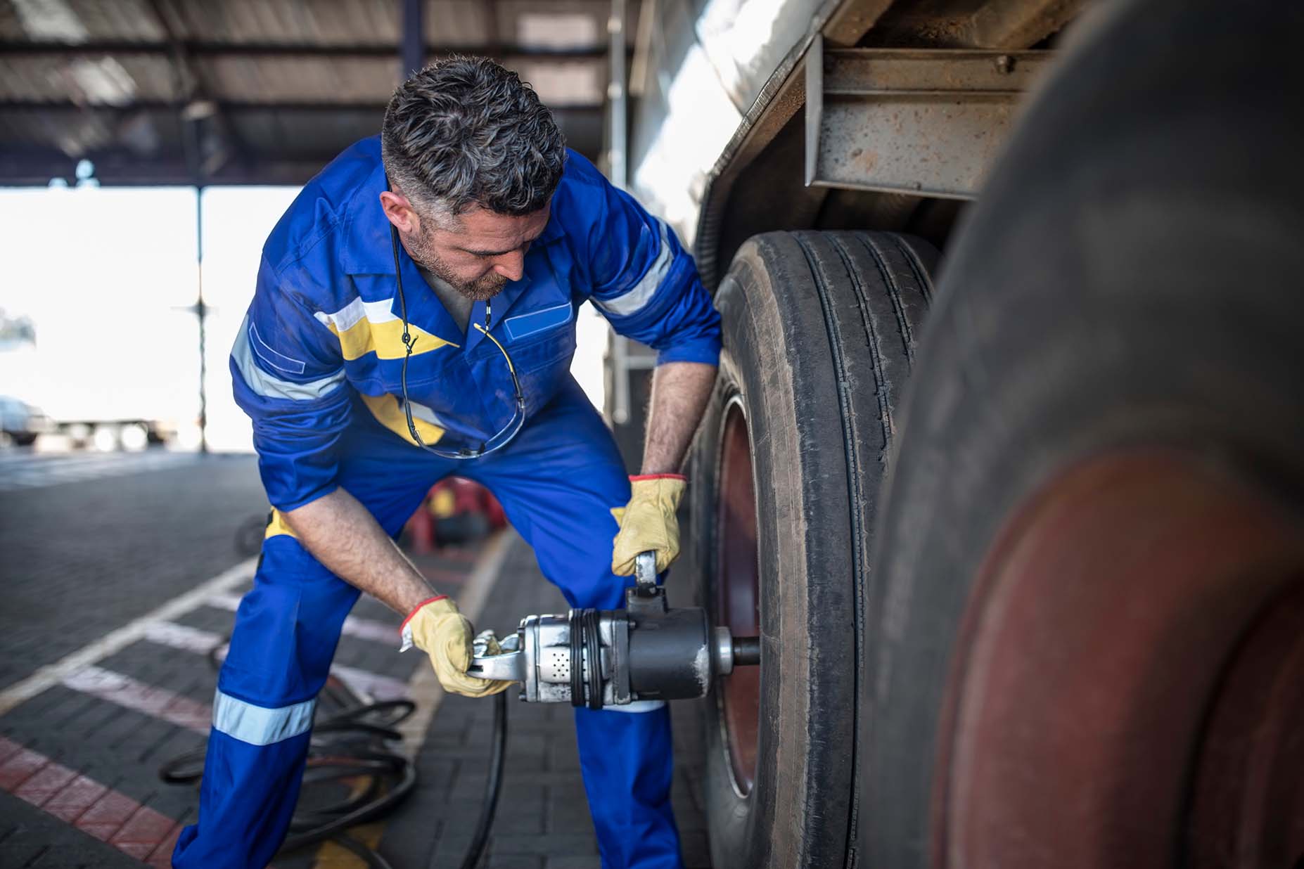A man checking the tires of a truck.